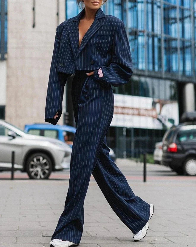 Vrouw draagt elegant marineblauw dames broekpak met blazer en pantalon, perfect voor zakelijke of avondoutfits.