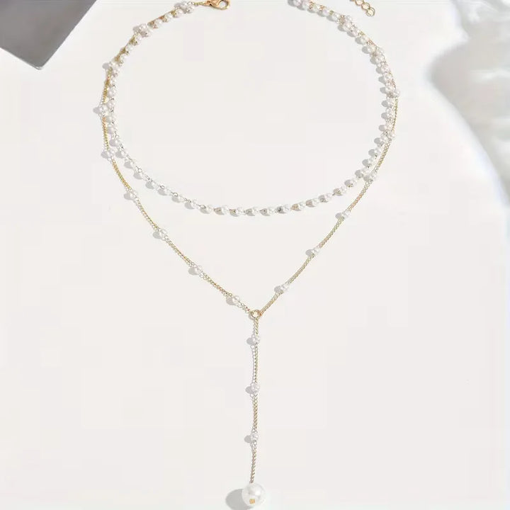 Goudkleurige Y-vormige ketting voor dames met glanzende parels; een elegant sieraad.