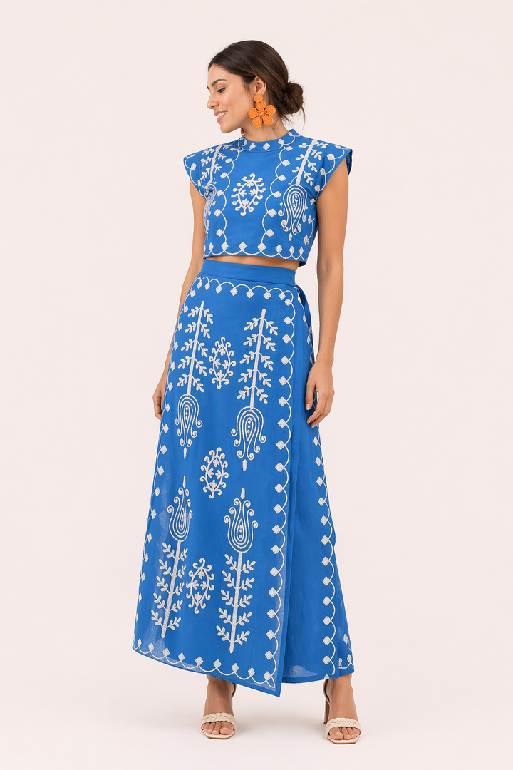 Model draagt een geborduurde tweedelige zomer set: een korte top en elegante midirok voor dames.