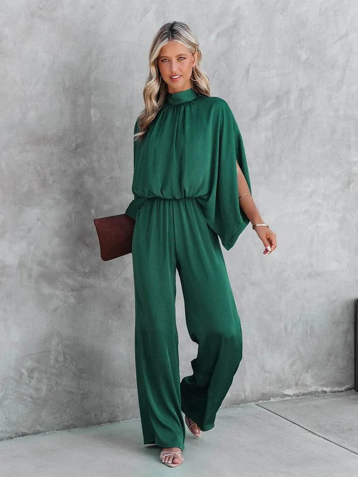 Elegante groene dames jumpsuit met chique capemouwen, perfect voor een speciale gelegenheid of avondfeest.
