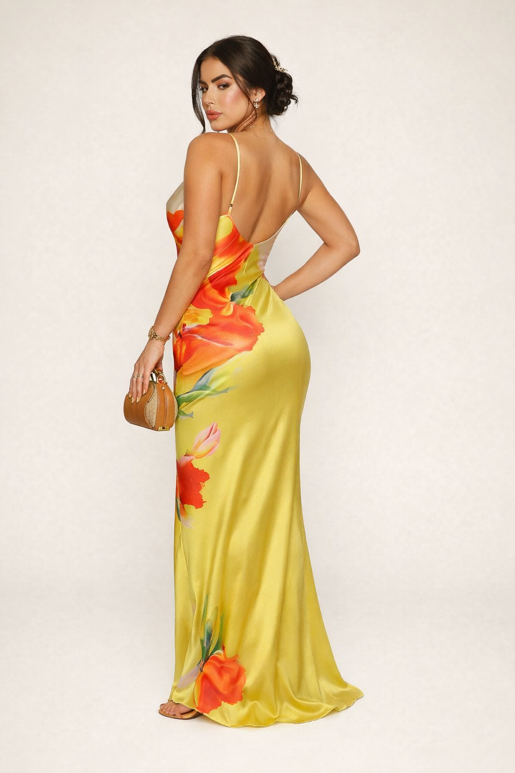Vrouwelijke gele zomerjurk met elegante bloemenprint en delicate bandjes, ideaal als feest- of avondjurk.