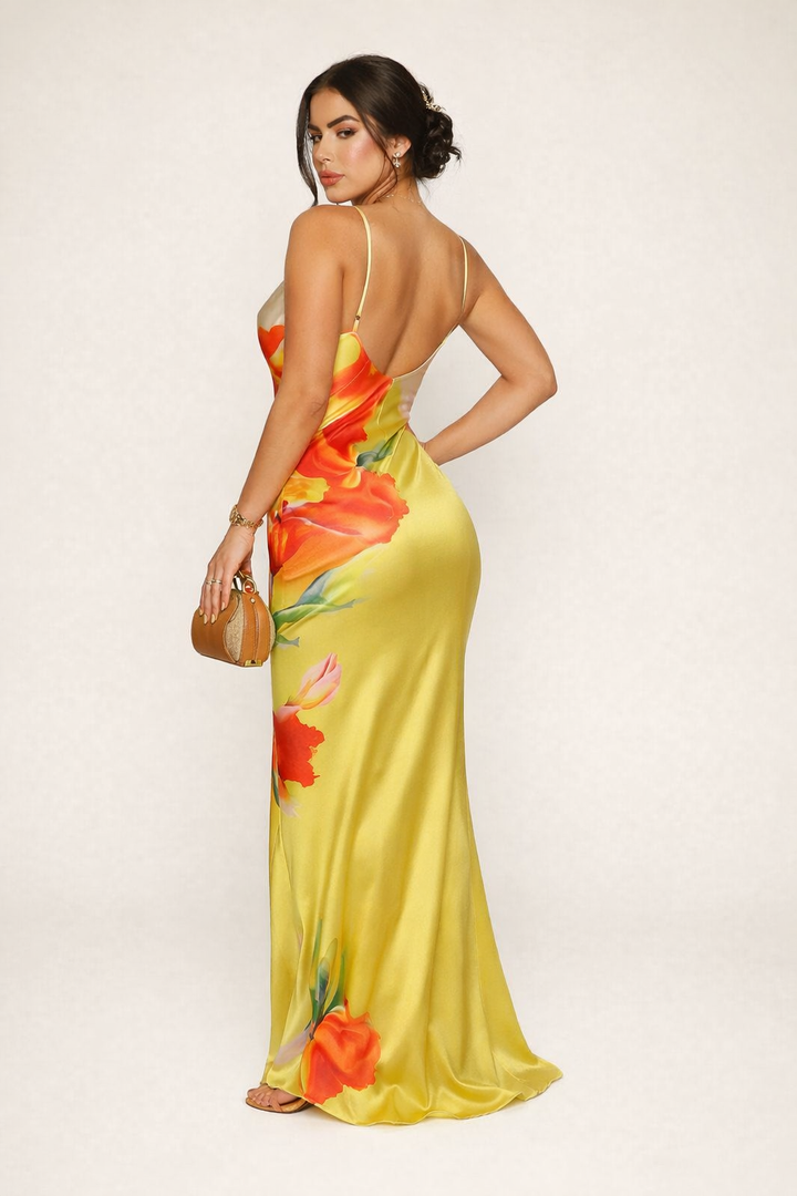 Vrouwelijke gele zomerjurk met elegante bloemenprint en delicate bandjes, ideaal als feest- of avondjurk.