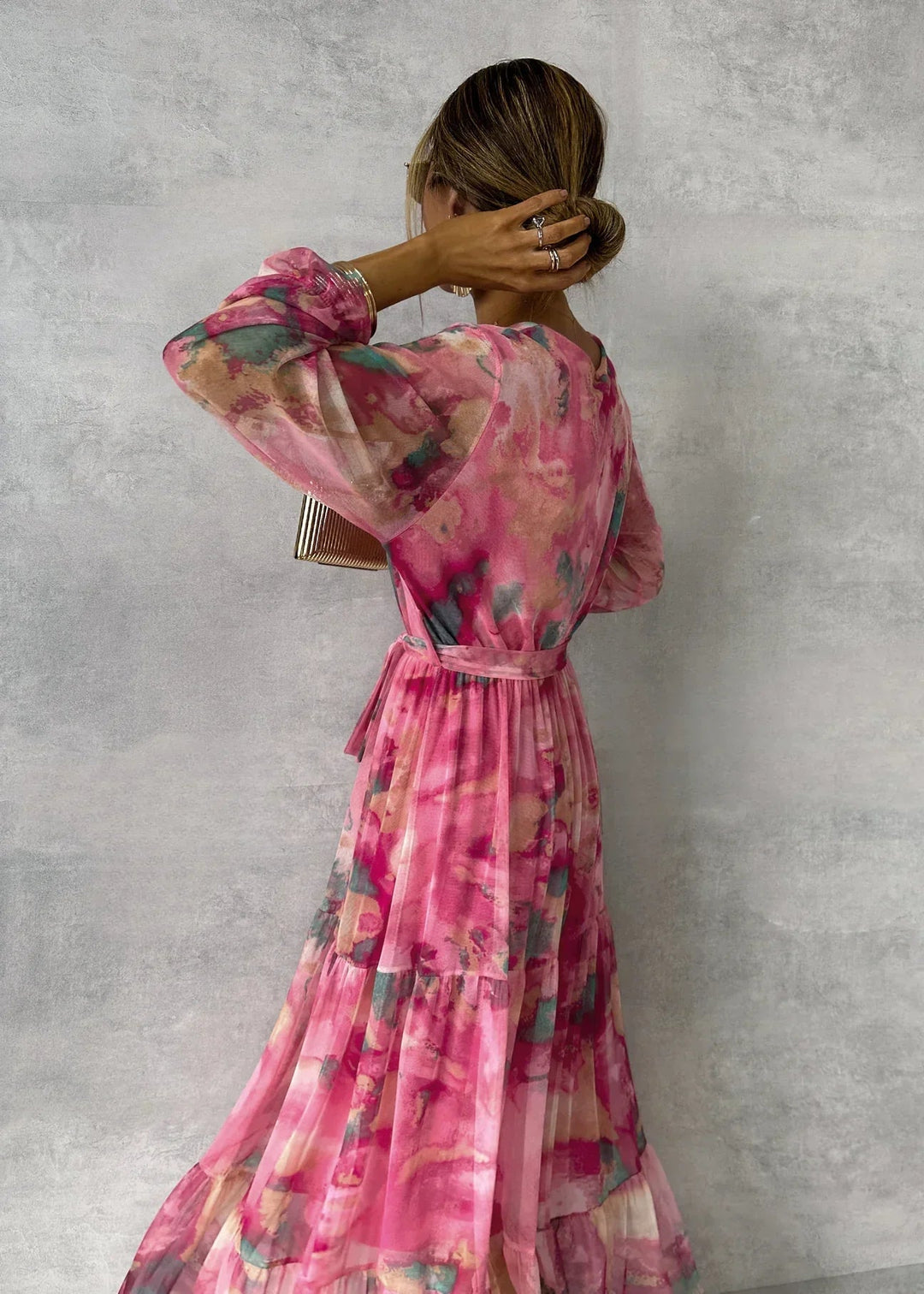Vrouwelijke wikkeljurk in roze met delicate bloemenprint en elegante lange mouwen, een veelzijdige damesjurk.