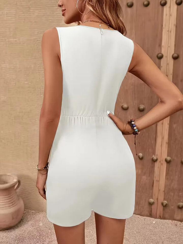 Mouwloze witte dames jumpsuit met V-hals, wijde pijpen en trendy kettingriem. Ideaal voor elegante zomerlooks.