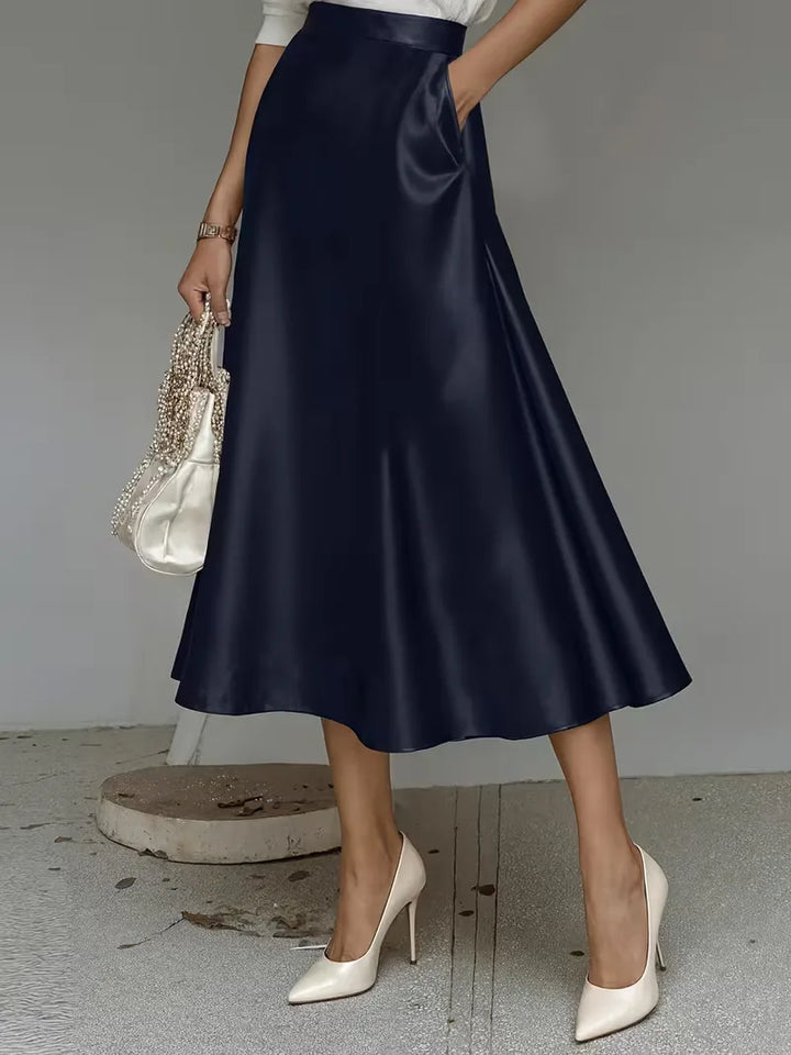 Stijlvolle roze satijnen rok, midi lengte en hoog getailleerd. Perfect voor lentemode en zomer casual.