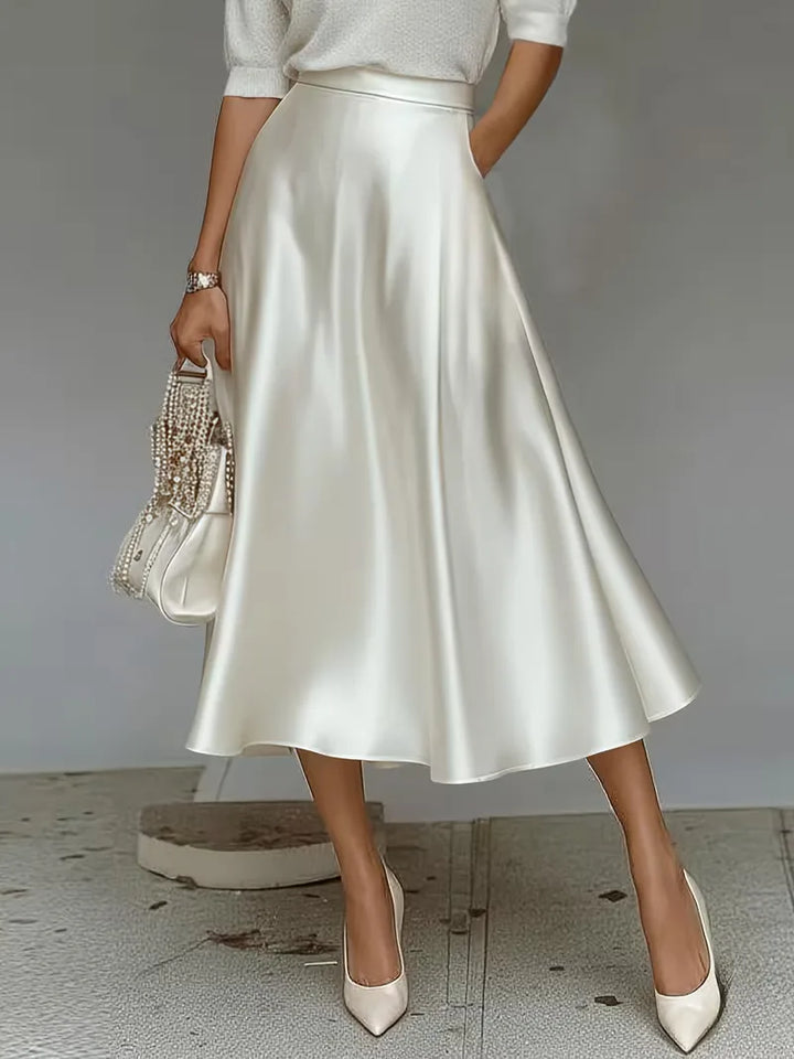 Goudkleurige satijnen rok, midi lengte, hoogtaille. Voegt een vleugje luxe toe aan je lentemode.