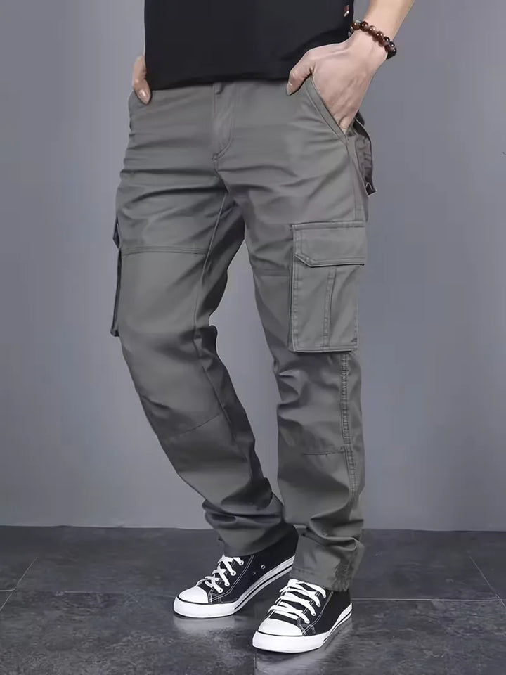 Model draagt trendy heren cargobroek met flapzakken, perfect voor een casual streetwear lente/herfst look.