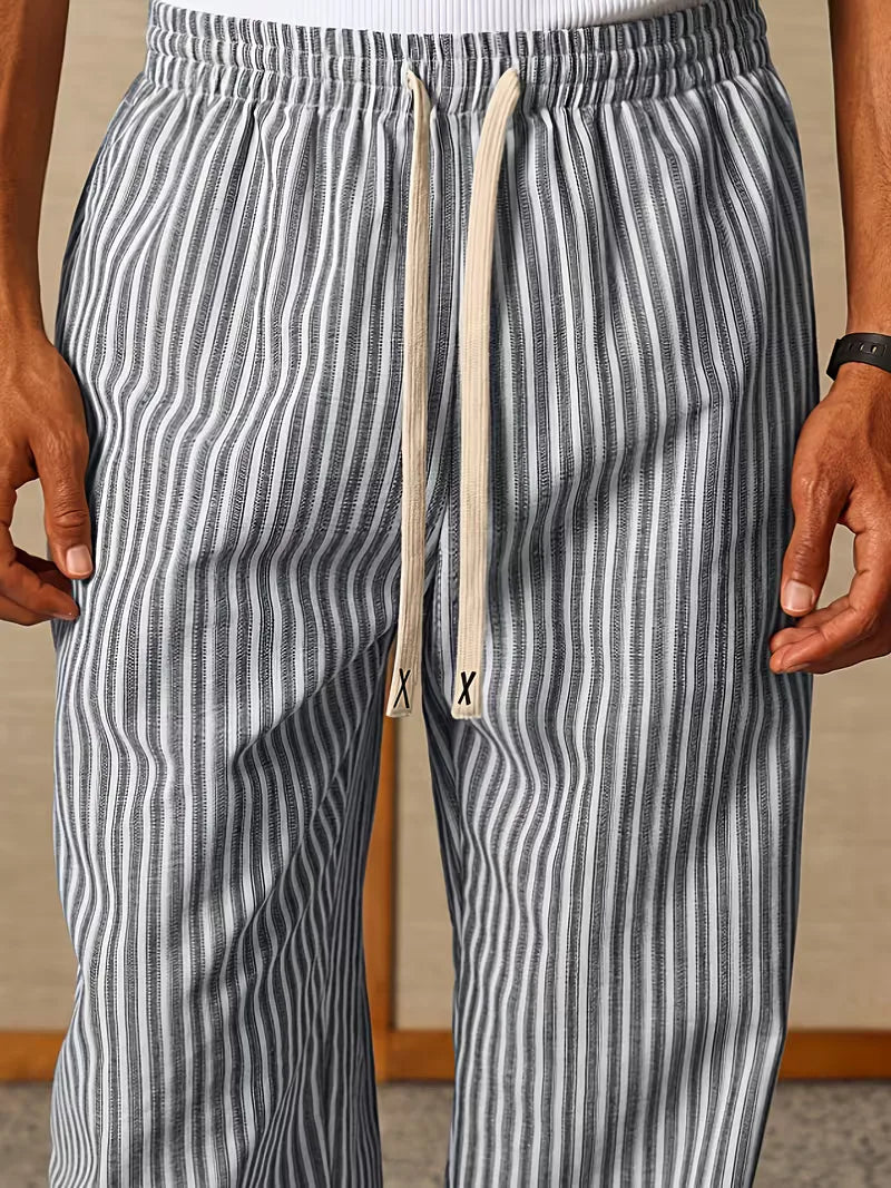 Gestreepte heren joggers nonchalant op de grond in een lichte, zomerse setting. Comfort en stijl.