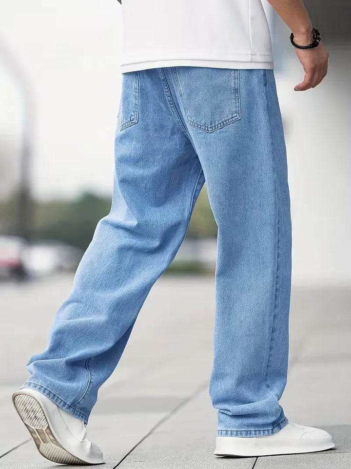 Model draagt comfortabele heren lichtblauwe straight jeans met mid-rise pasvorm, een essentiële broek.