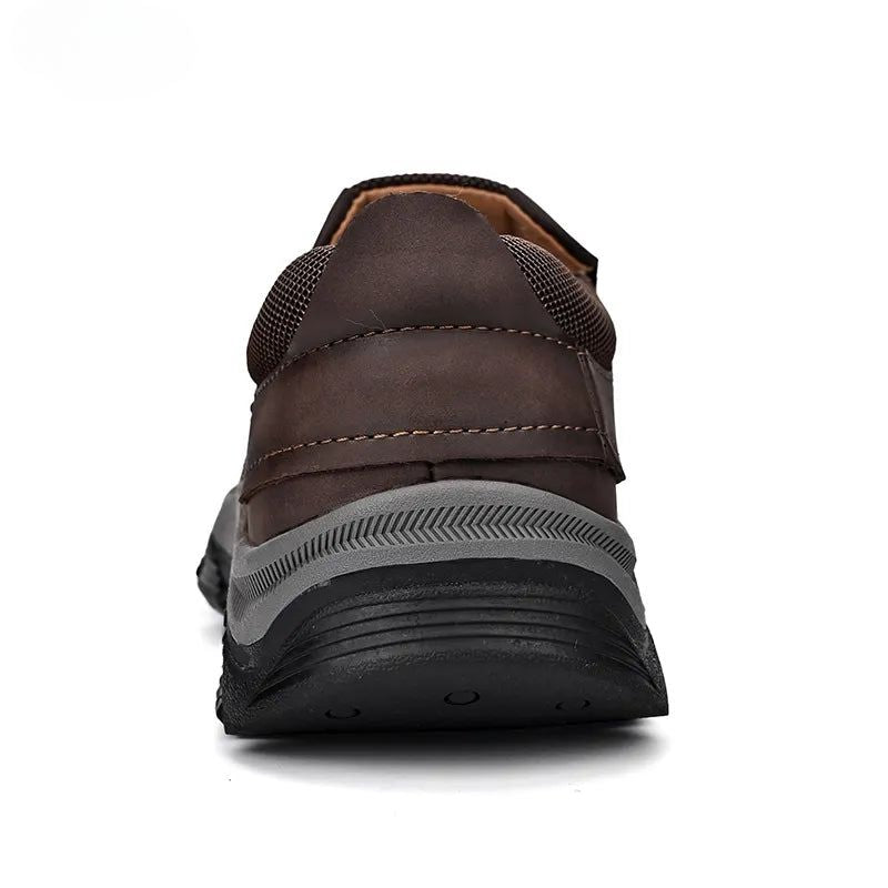 Zwarte orthopedische heren instappers op een houten vloer, benadrukkend de veelzijdigheid chic/casual.