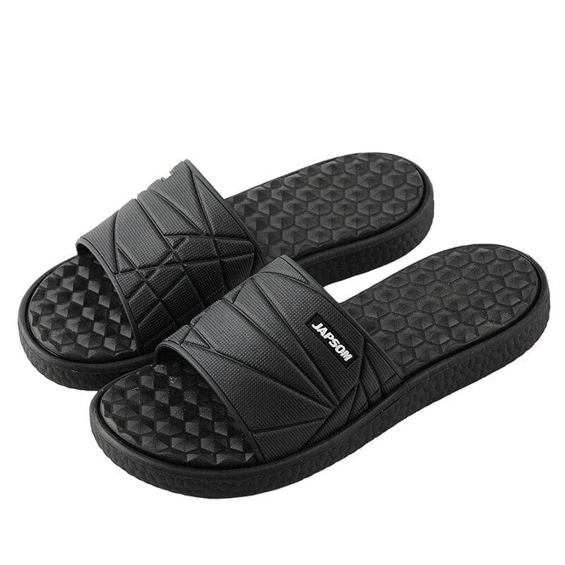 Paar orthopedische herenslippers in beige, op een stenen pad, klaar voor een wandeling.