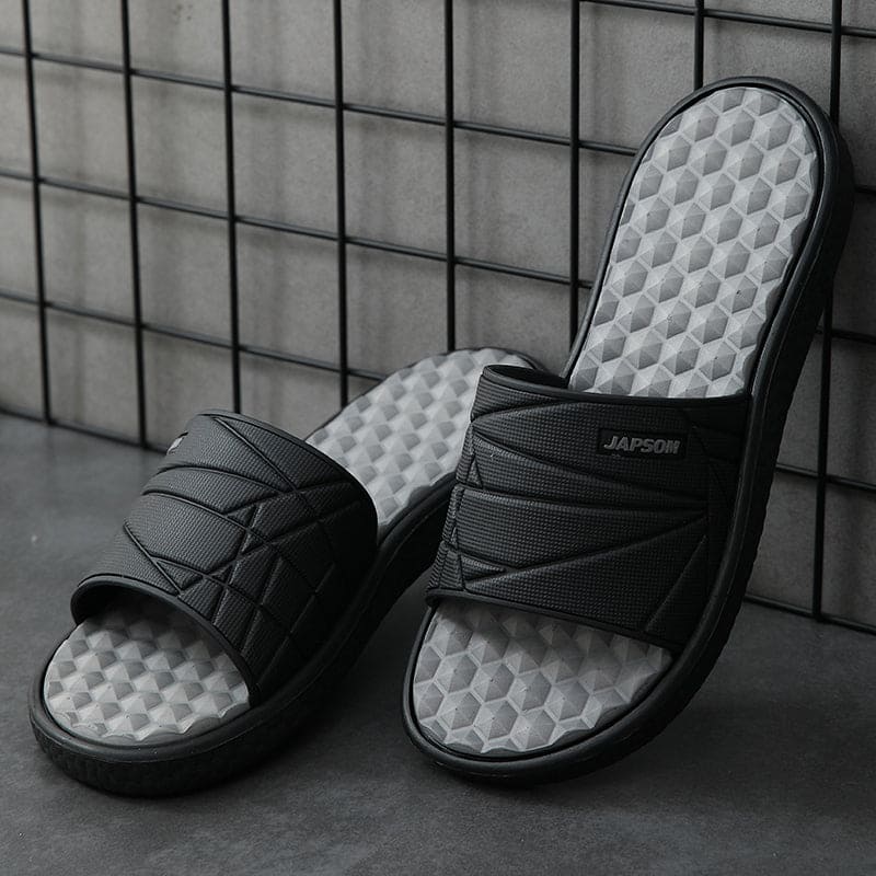 Zijwaarts beeld van een orthopedische herenslipper, benadrukt de vorm van het voetbed.