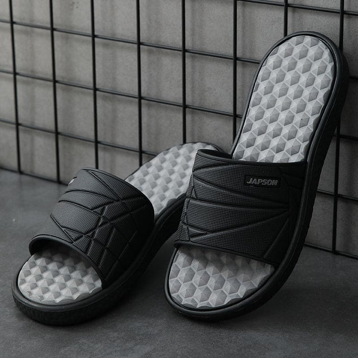 Zijwaarts beeld van een orthopedische herenslipper, benadrukt de vorm van het voetbed.