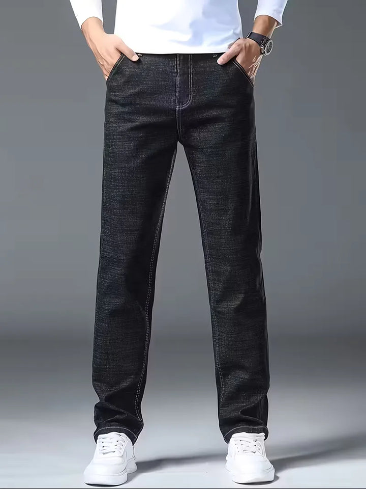 Close-up: Zichtbare stiksels op donkerblauwe heren straight jeans, benadrukt vakmanschap en detail.