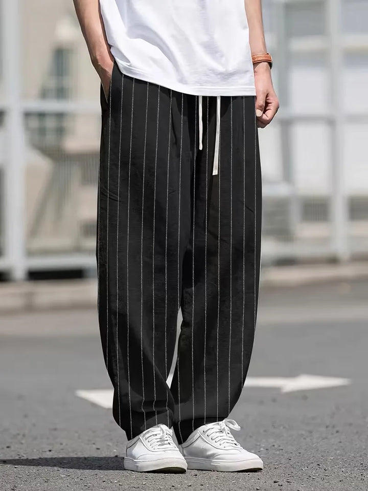 Trendy heren pantalon met verticale strepen en wijde pasvorm, in zwart, voor een moeiteloze stijl.