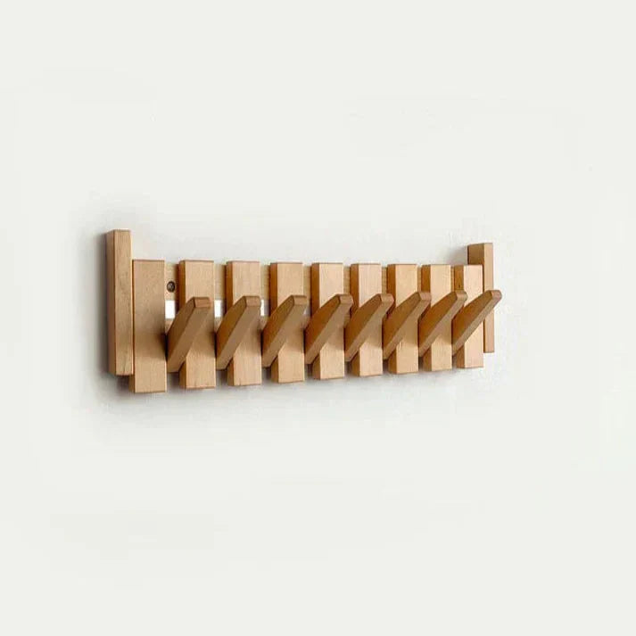 Houten wandkapstok met acht opklapbare toetsen, als decoratief en praktisch element aan de muur.