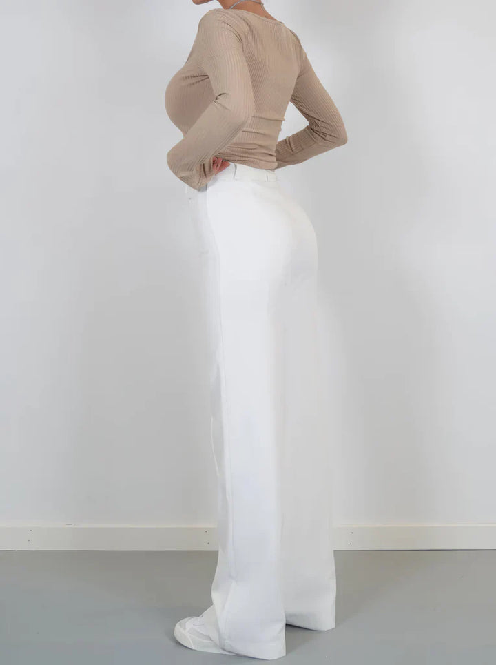 Model draagt de Hoymans slim fit pantalon met wijde pijpen, gecombineerd met een blouse, zakelijke look.