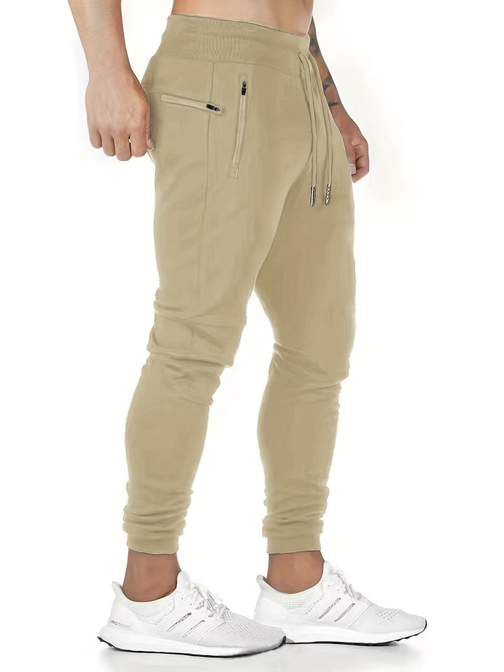 "Kastanjebruine heren joggingbroek van lichtgewicht polyester met ritszakken en trekkoord, ideaal voor lente en herfst."