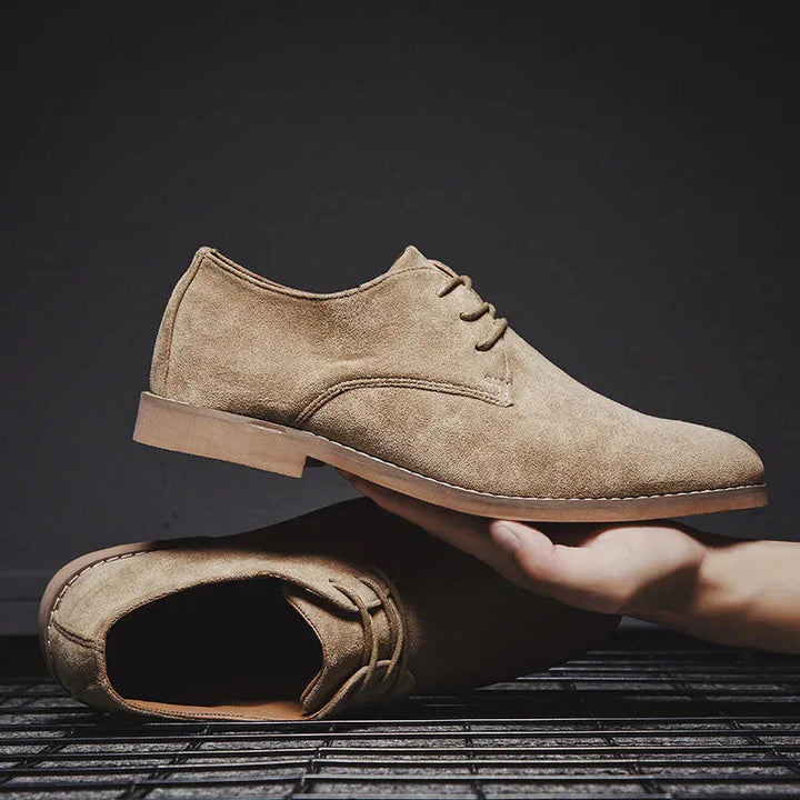 Detailopname van bruine suède oxford schoenen voor heren met fijne stikseldetails.