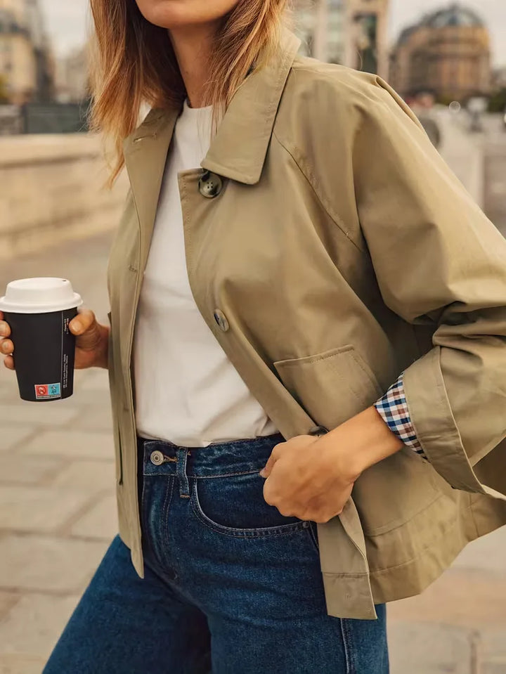 Klassieke khaki damestrenchcoat met elegante geruite voering, perfect als overgangsjas voor lente/herfst.