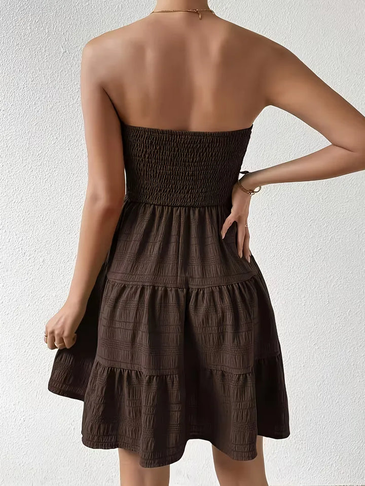 Detail van de smocked bodice op de koffiebruine A-lijn zomerjurk, benadrukt de pasvorm.