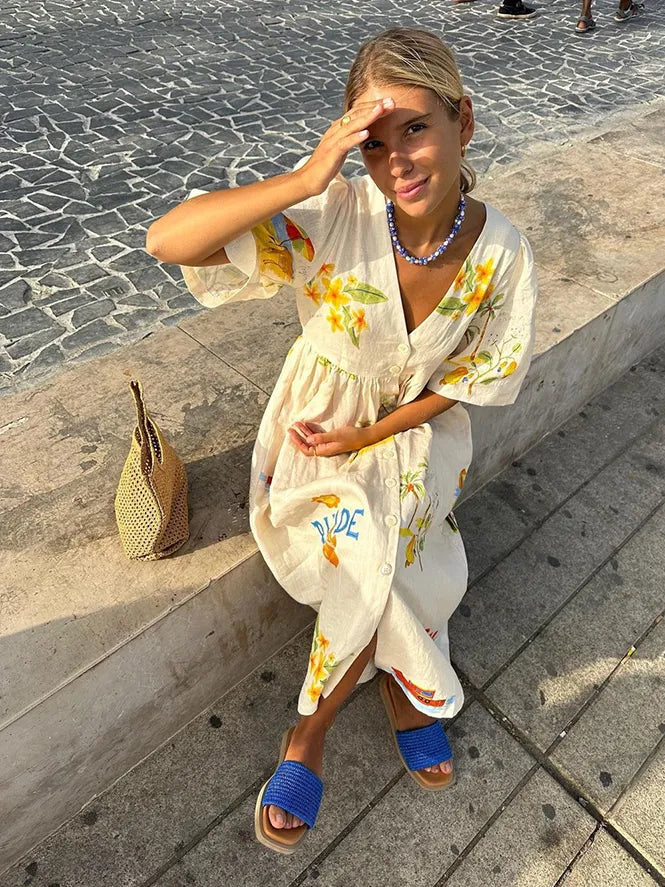 "Luchtige linnen zomerjurk met citroen- en bloemenprint, pofmouwen en V-hals, perfect voor warme dagen."