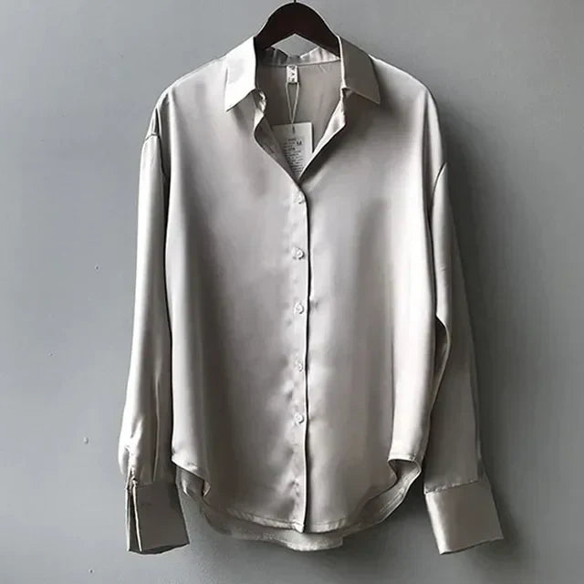 Celeste satijnen blouse dames, vloeiende stof, lange mouwen, subtiele glans, elegante kraag, verfijnde stijl.