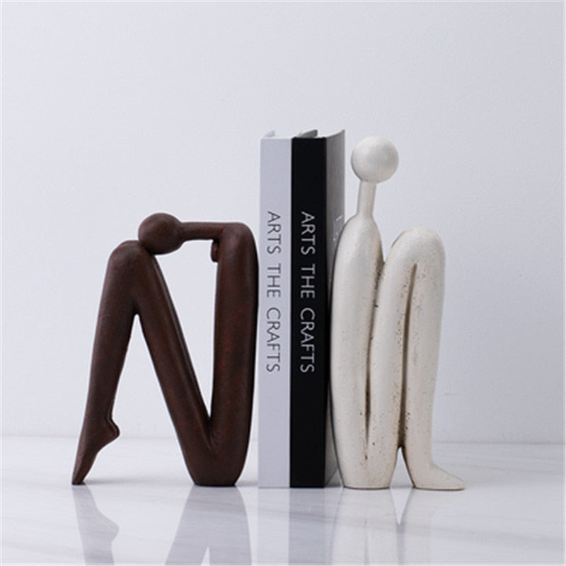 Set decoratieve metalen boeksteunen (wit/bruin) voor een moderne boekenplank. Houdt boeken georganiseerd met stijl.