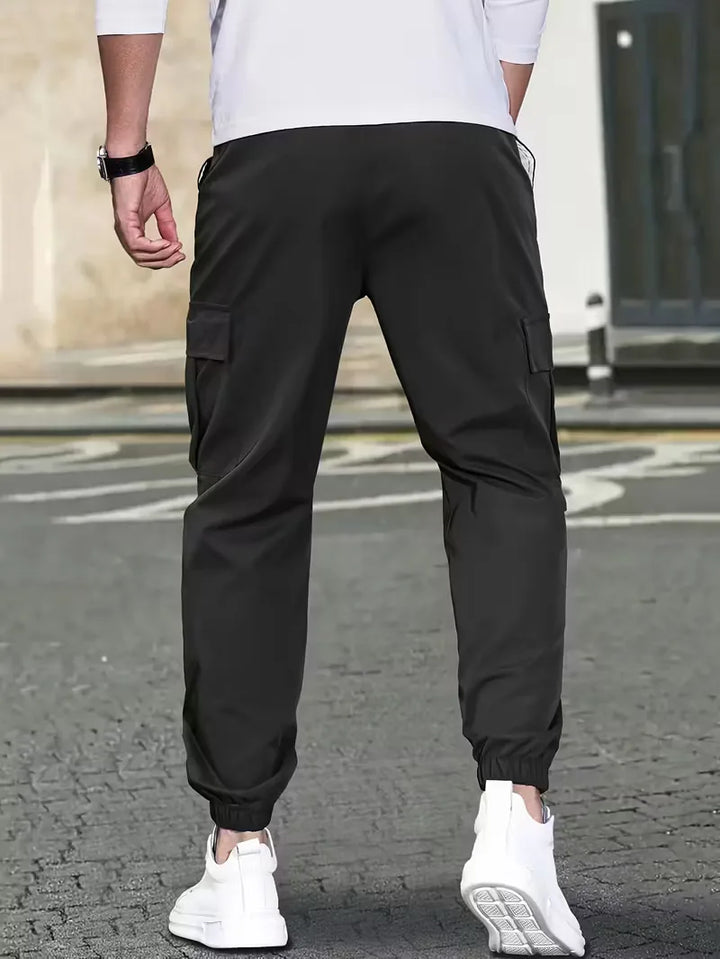 Zwarte heren cargo broek, taps toelopend, met elastische boorden en klepzakken. Ideaal voor casual gebruik.