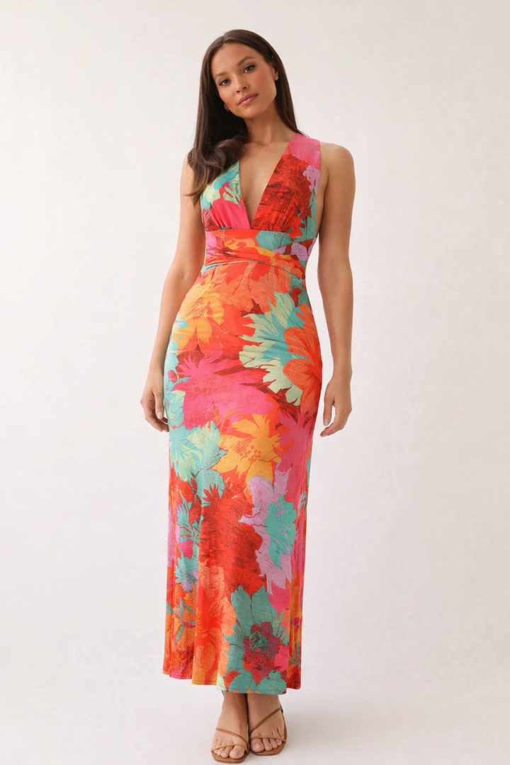 Oranje dames maxijurk met bloemenprint, elegante halternek en slanke pasvorm. Perfecte zomerjurk.