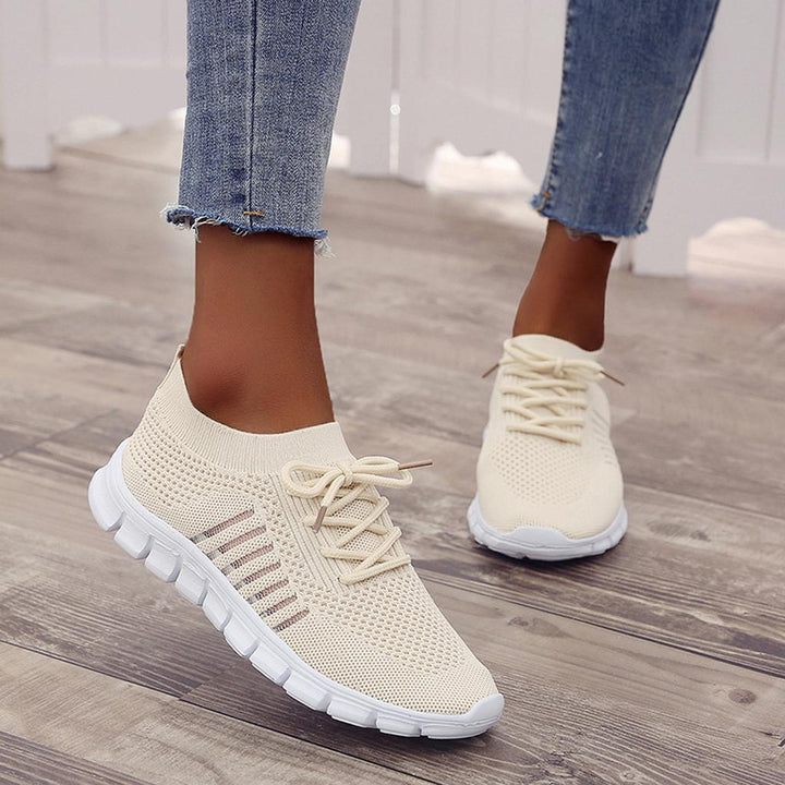 Vrouw met orthopedische sneakers aan de voeten, staand in een park, toont het sportieve en ondersteunende design.