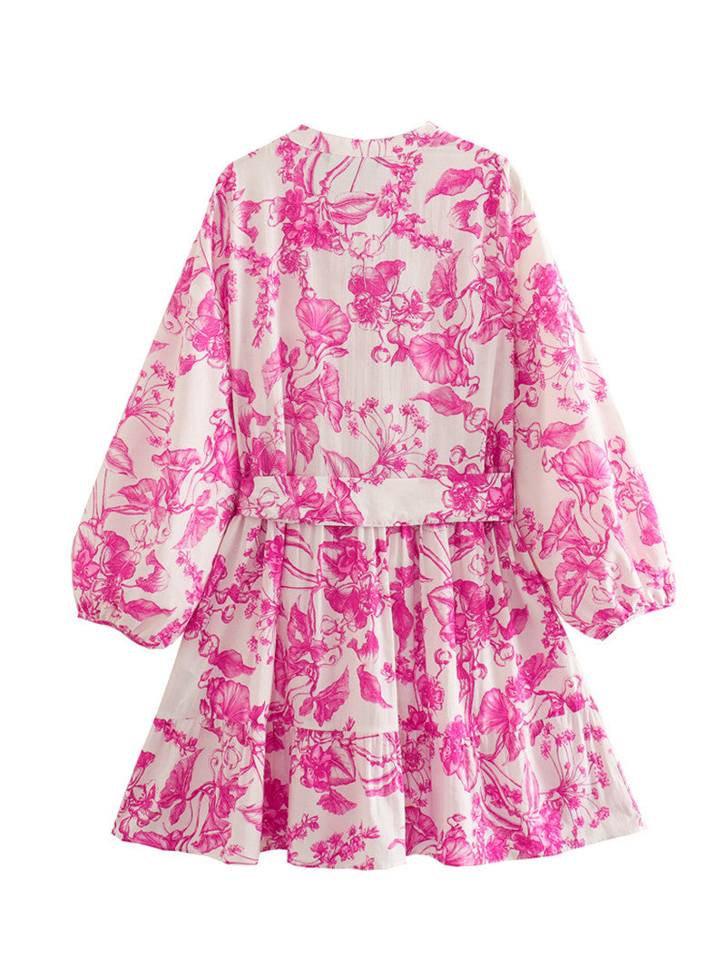 Levendige roze gebloemde damesjurk met korte lengte en vrouwelijke print. Een chique zomerjurk met verstelbare taille.