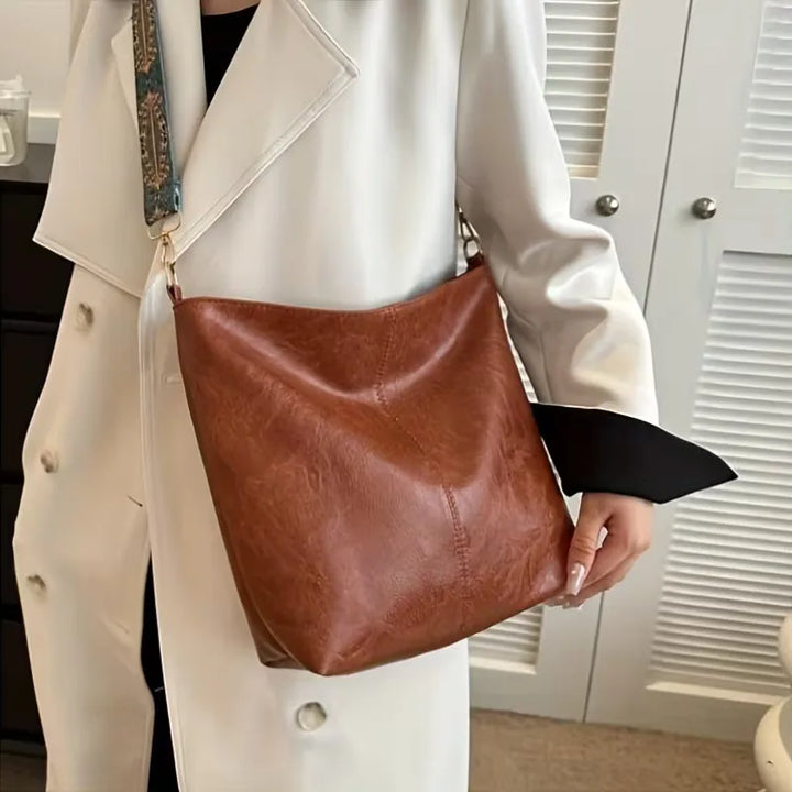 Ruime schoudertas voor dames, voorzien van ritssluiting en een modieuze kleurrijke band. Praktisch en elegant.