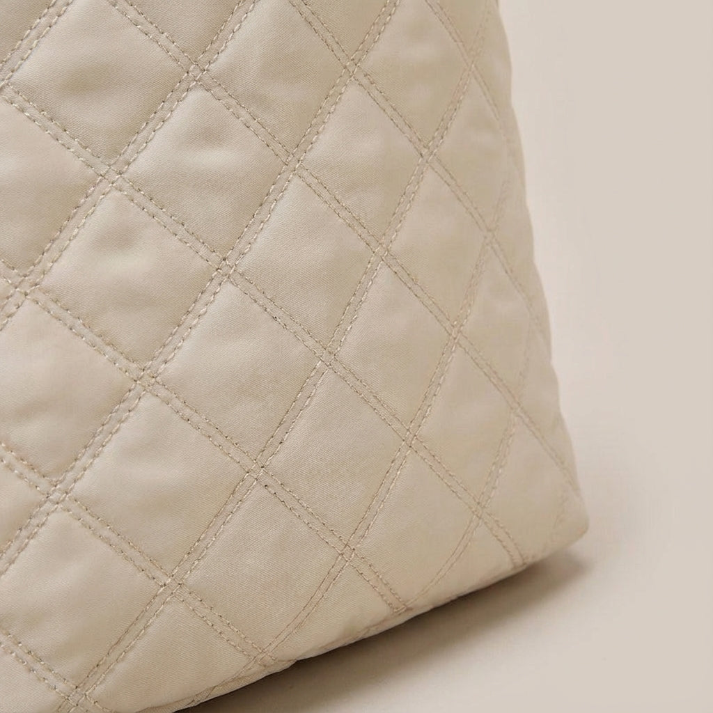 Gedetailleerde close-up van de zachte, gewatteerde stof van de trendy Quiltiva weekendtas.