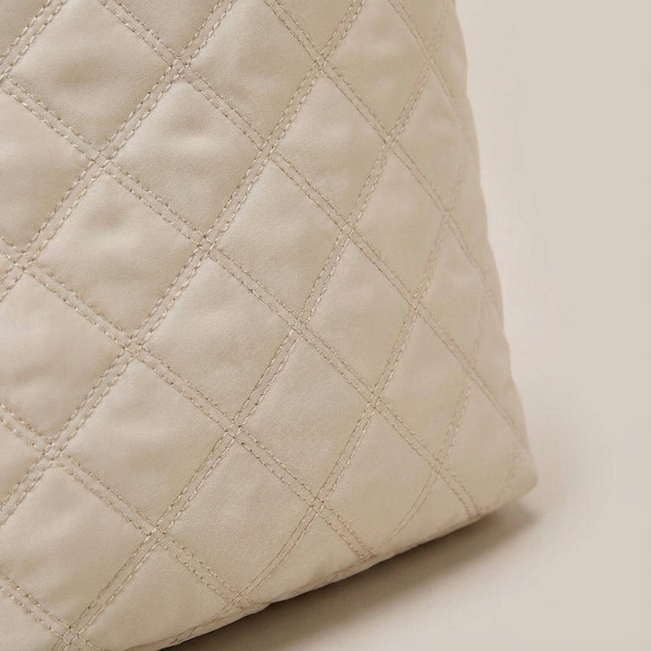 Gedetailleerde close-up van de zachte, gewatteerde stof van de trendy Quiltiva weekendtas.