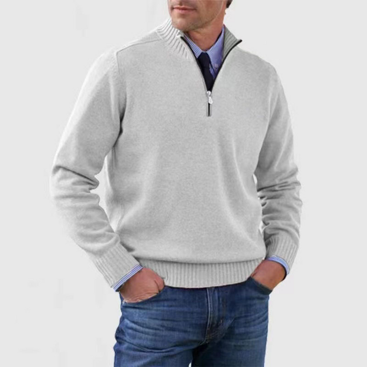 Man draagt stijlvolle herenpullover met halverits, combineert mode en casual elegantie.