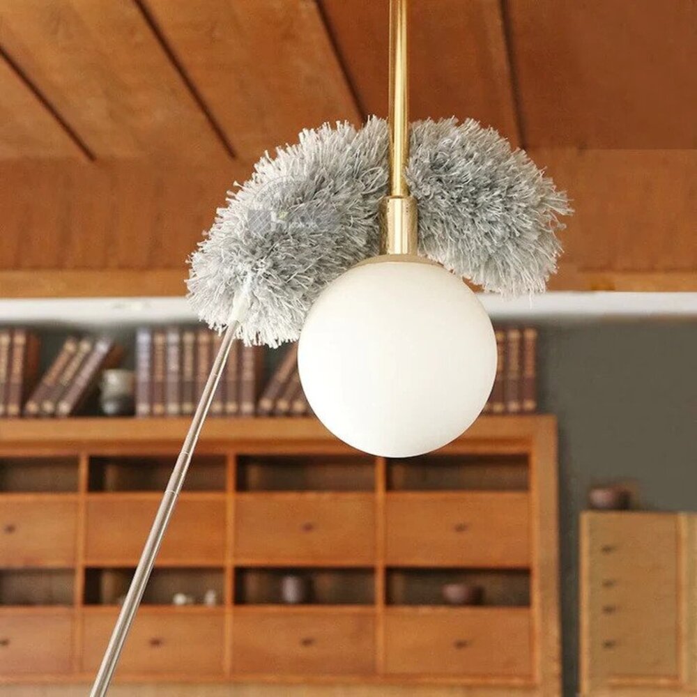 Vrouw gebruikt de telescopische plumeau om plafonds te reinigen. Een wonderplumeau voor hoogtes schoonmaken.