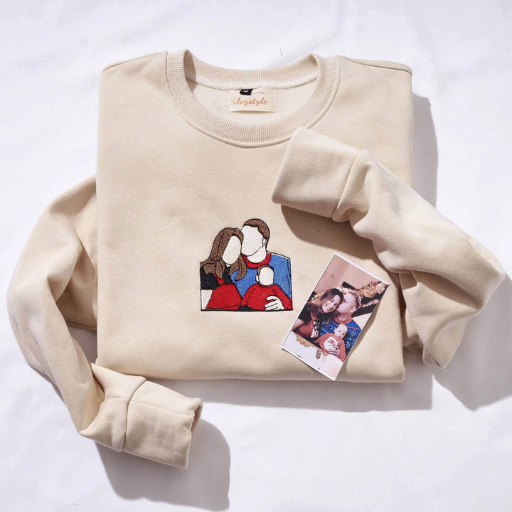 Man en vrouw dragen matching geborduurde StitchPortrait sweatshirts van een dierbare gezinsfoto.