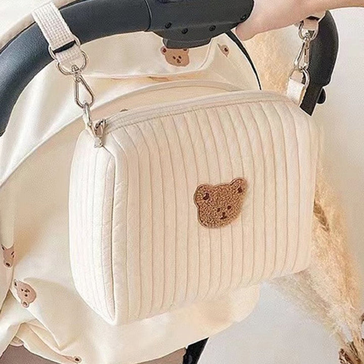 Neutrale unisex luiertas met berenprint, hangend aan een kinderwagen. Ideaal voor reizen met babybenodigdheden.