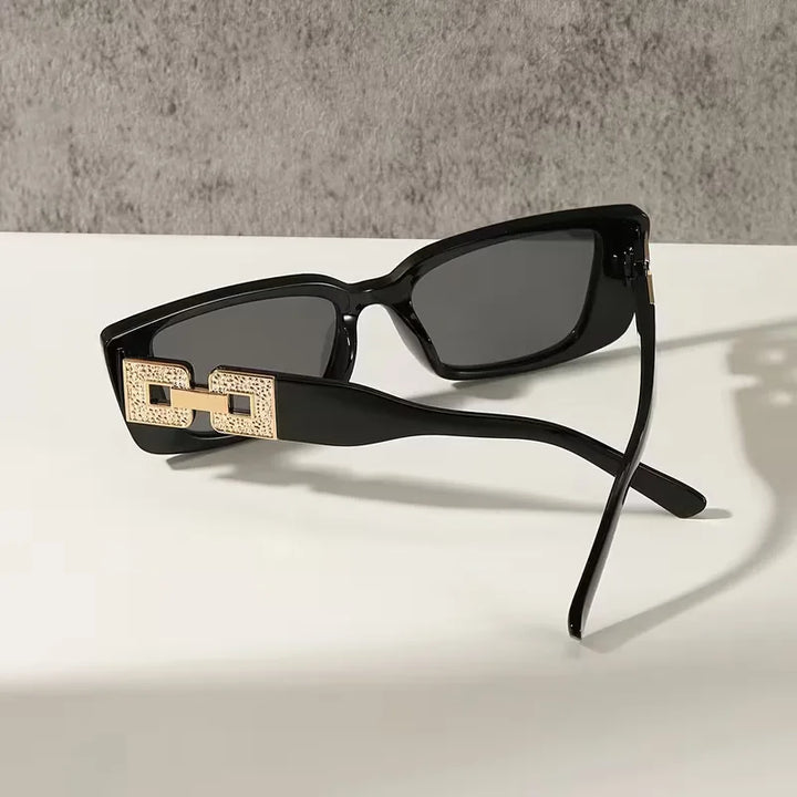 Rechthoekige unisex zonnebril, zwart polycarbonaat frame. Biedt optimale UV-bescherming en een modieuze, elegante look.