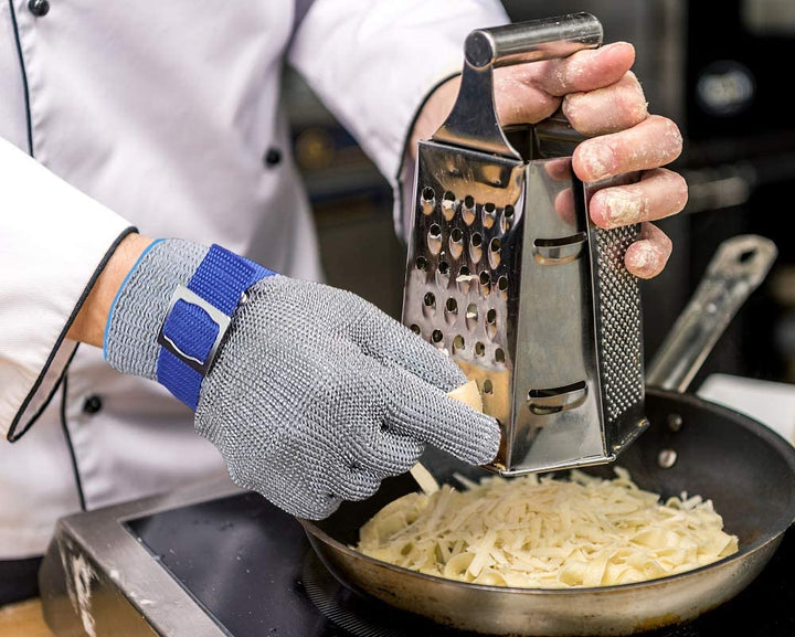 Model draagt een unisex snijbestendige handschoen tijdens het snijden van voedsel in de keuken.