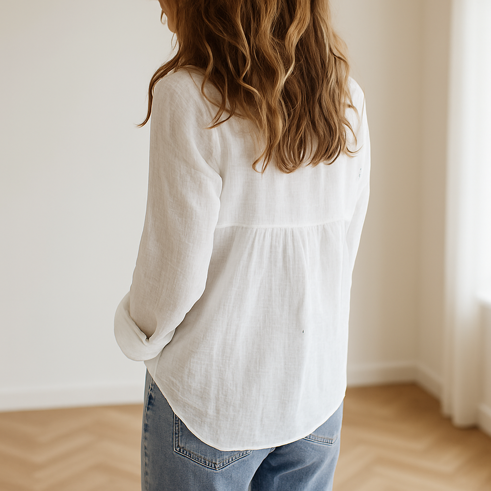 vrouw draagt luchtige witte linnen blouse met lange mouwen in lichte ruimte, ideaal voor een stijlvolle zomerse outfit