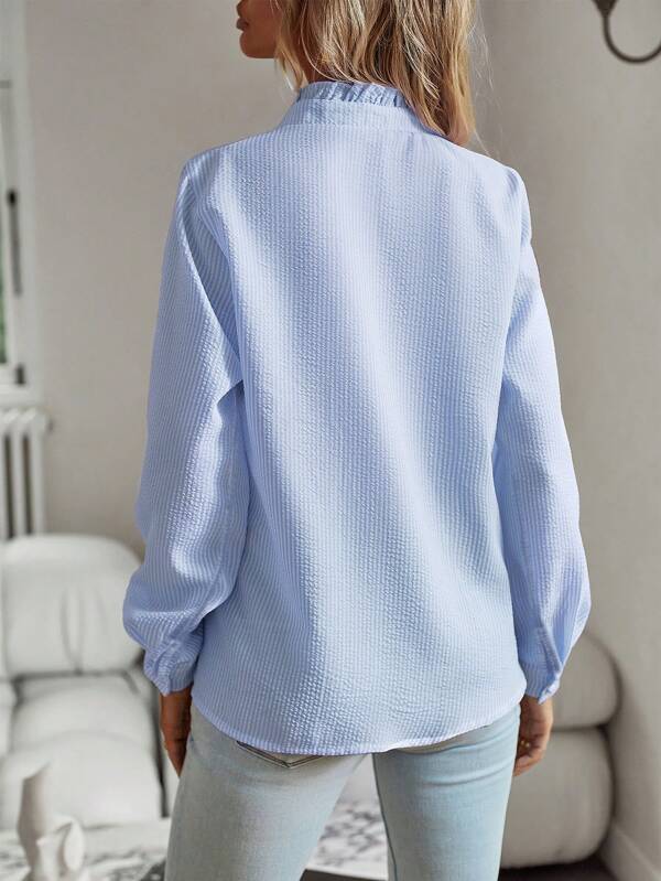 Vrouw in trendy blouse met subtiele streepjes, ruches, en elegante knoopsluiting voor veelzijdige damesmode