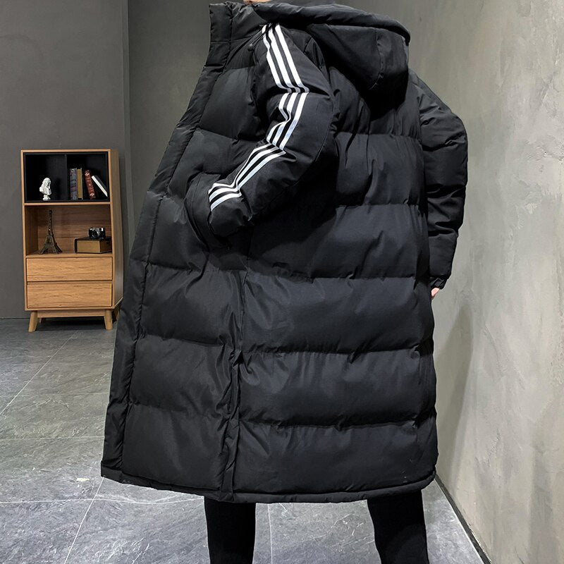 Man draagt stijlvolle lange gewatteerde herenjas met capuchon, ideaal voor comfortabele en warme winterkleding.