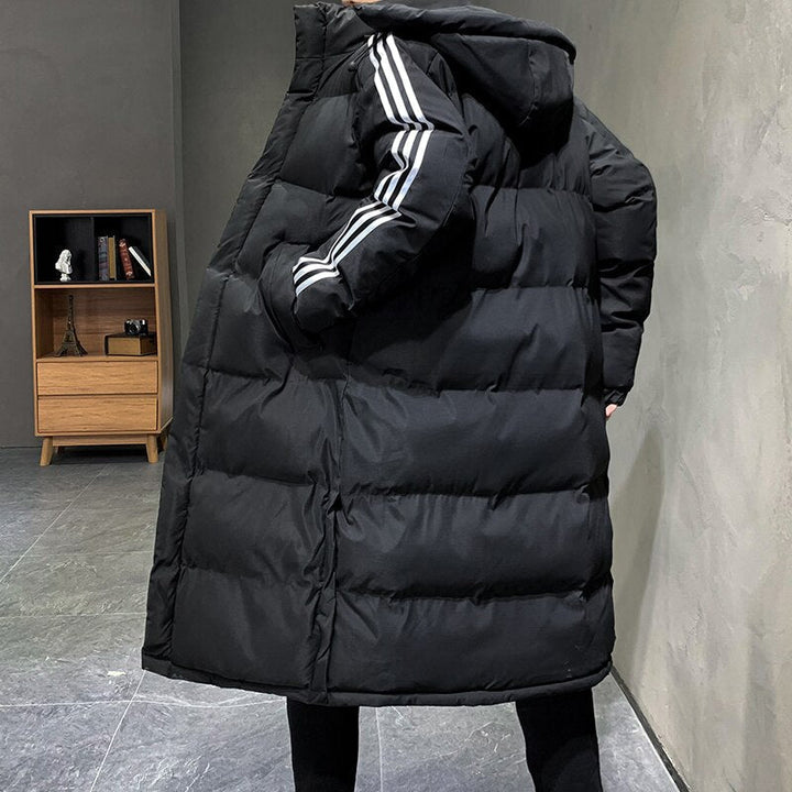 Man draagt stijlvolle lange gewatteerde herenjas met capuchon, ideaal voor comfortabele en warme winterkleding.