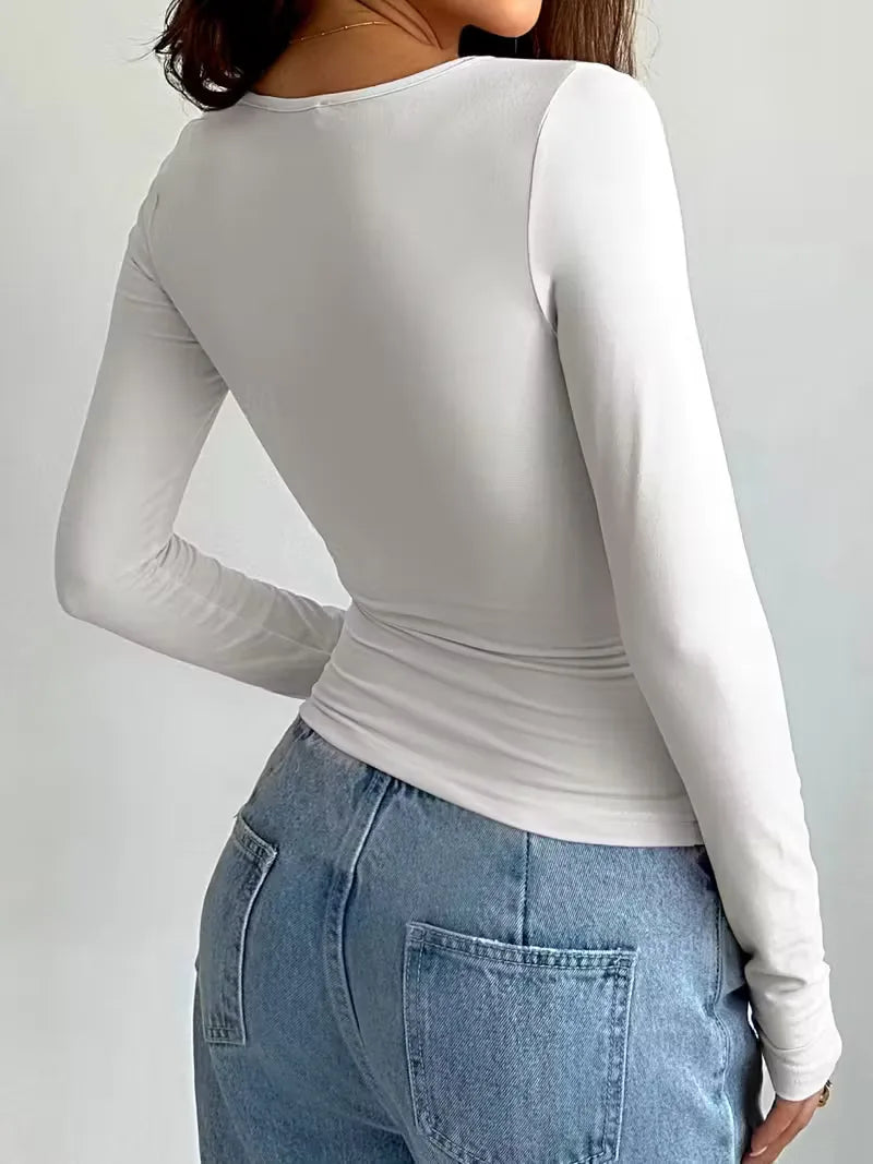 Stijlvolle witte slimfit longsleeve voor dames, met ronde hals. Perfect voor comfortabele, casual zomer- of lente outfits.
