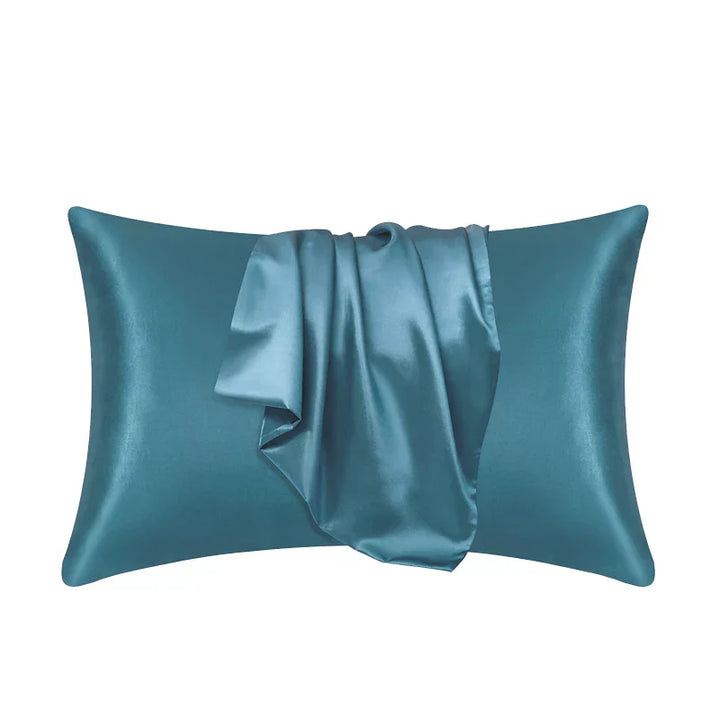 Witte polyester kussensloop naast een bedlampje, creëert rustige slaapkamer ambiance.