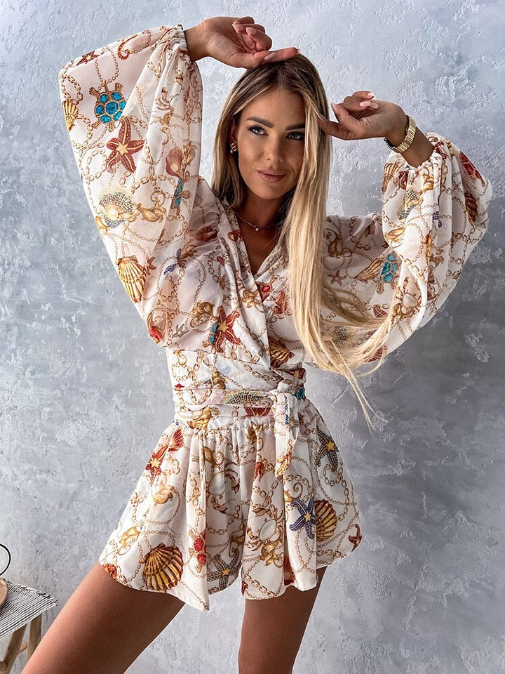 "Zomerse playsuit met V-hals, fruit- en bladmotieven, kleurrijke tropische print, accentueert silhouet en biedt comfort."