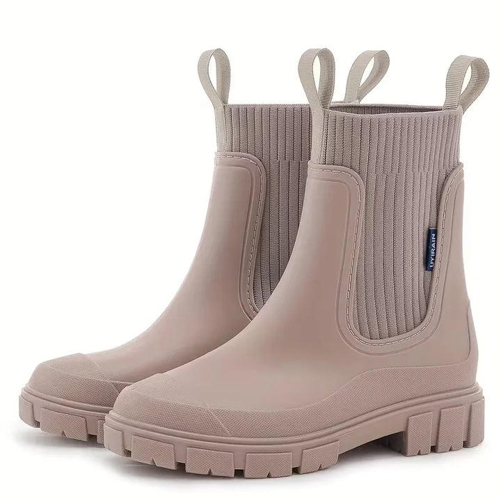 Close-up van beige dames Chelsea boot, toont detail van elastische inzet en stevige platte zool.