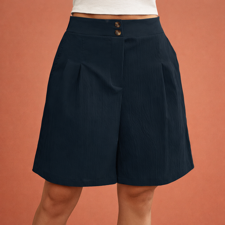 Zwarte geplooide shorts met hoge taille, gedragen door een model. Elegante dameskorte broek, casual chic.